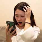 スマホを見て驚く女性
