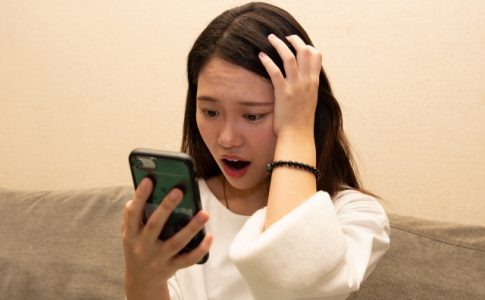 スマホを見て驚く女性
