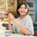スマホを手に笑顔の女性
